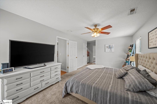 bedroom with ceiling fan, a textured ceiling, light carpet, visible vents, and baseboards