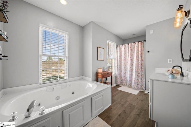 bathroom with a whirlpool tub, wood finished floors, vanity, and a shower with curtain