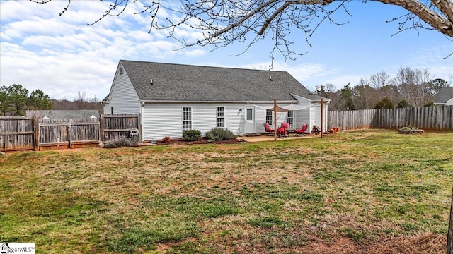 rear view of house featuring a yard, roof with shingles, a patio area, and a fenced backyard