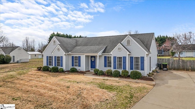 view of front of home with a shingled roof, fence, and a front yard