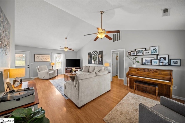 living room featuring lofted ceiling, baseboards, visible vents, and wood finished floors