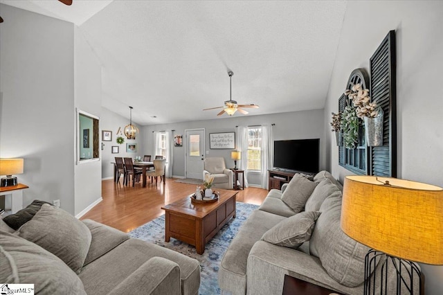 living room with baseboards, a ceiling fan, lofted ceiling, wood finished floors, and a textured ceiling