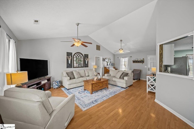 living area with visible vents, vaulted ceiling, and wood finished floors