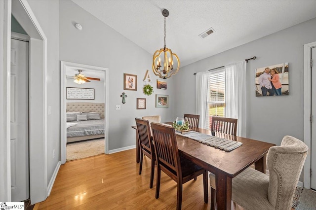 dining area with a notable chandelier, visible vents, baseboards, vaulted ceiling, and light wood finished floors