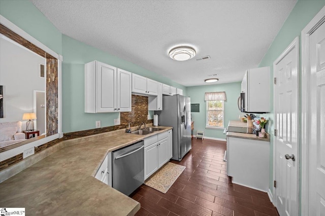 kitchen featuring dark wood-type flooring, a sink, visible vents, white cabinetry, and appliances with stainless steel finishes