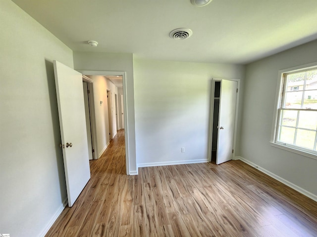 unfurnished bedroom featuring visible vents, baseboards, and wood finished floors