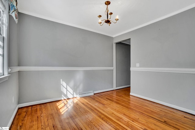 empty room featuring visible vents, a notable chandelier, baseboards, and wood finished floors