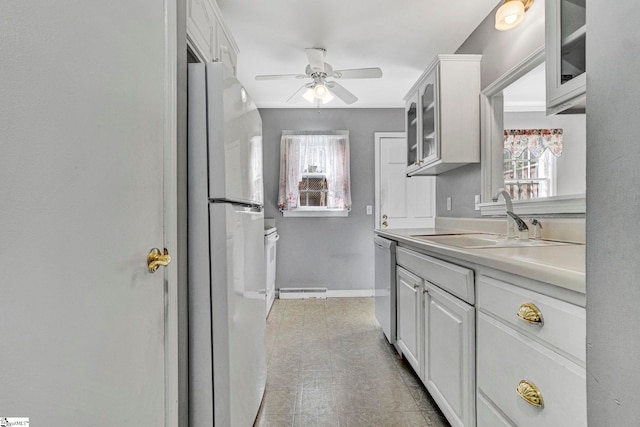 kitchen with light countertops, glass insert cabinets, freestanding refrigerator, a sink, and dishwashing machine