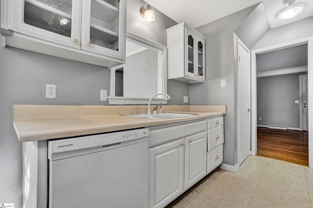 kitchen with a sink, white cabinets, light countertops, dishwasher, and glass insert cabinets