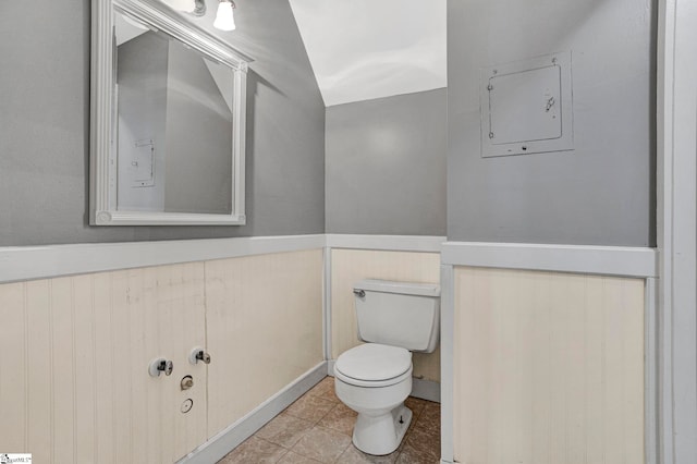 bathroom featuring electric panel, wainscoting, toilet, and tile patterned floors