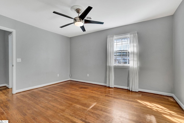 unfurnished room featuring a ceiling fan, baseboards, and wood finished floors