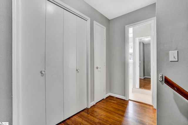 corridor featuring baseboards and wood finished floors