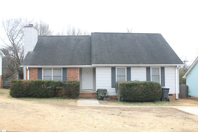 view of front facade with roof with shingles, brick siding, and a chimney