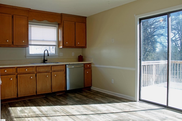 kitchen featuring dishwasher, light countertops, a sink, and brown cabinets