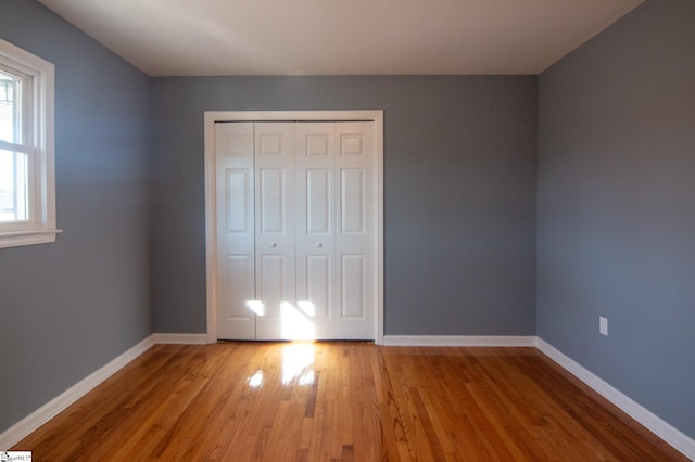 unfurnished bedroom with a closet, baseboards, and wood finished floors