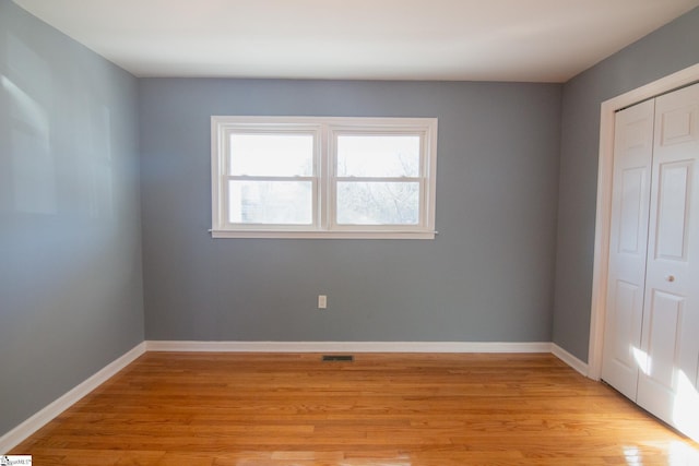 unfurnished bedroom featuring light wood-style flooring, visible vents, baseboards, and a closet