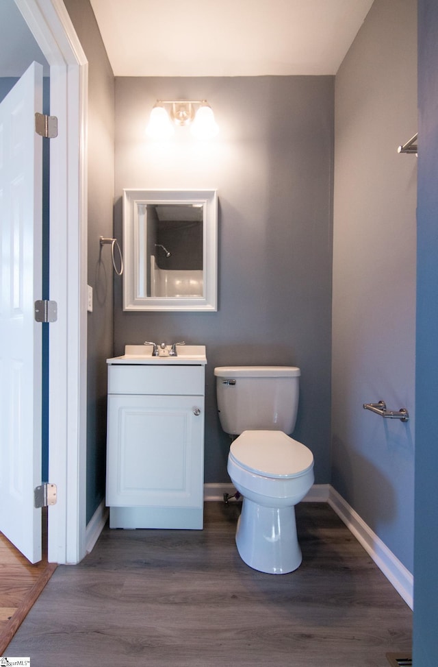 bathroom with toilet, baseboards, wood finished floors, and vanity