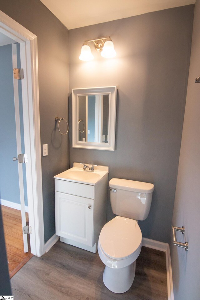 bathroom featuring toilet, vanity, baseboards, and wood finished floors