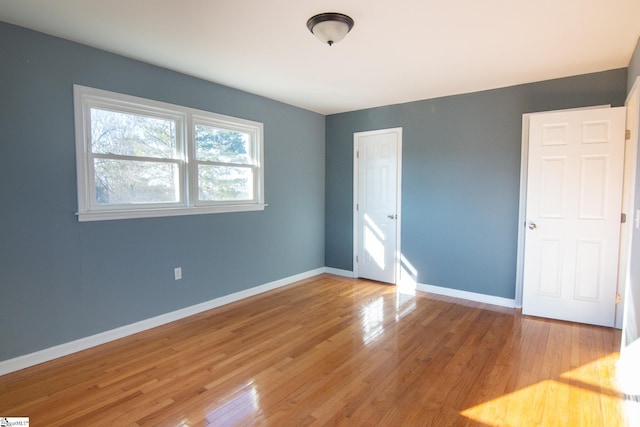 unfurnished bedroom featuring light wood-style floors, a closet, and baseboards