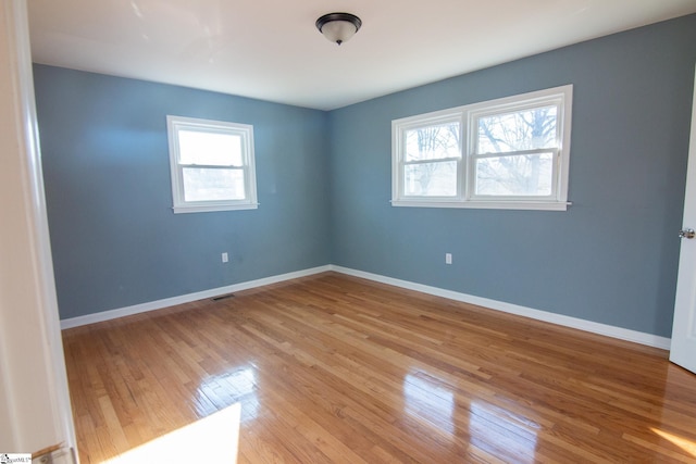 unfurnished room with visible vents, light wood-style flooring, and baseboards