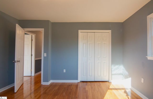 unfurnished bedroom featuring a closet, baseboards, and wood finished floors