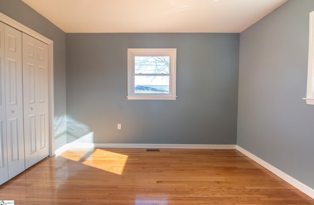 unfurnished bedroom with light wood-style floors, baseboards, visible vents, and a closet