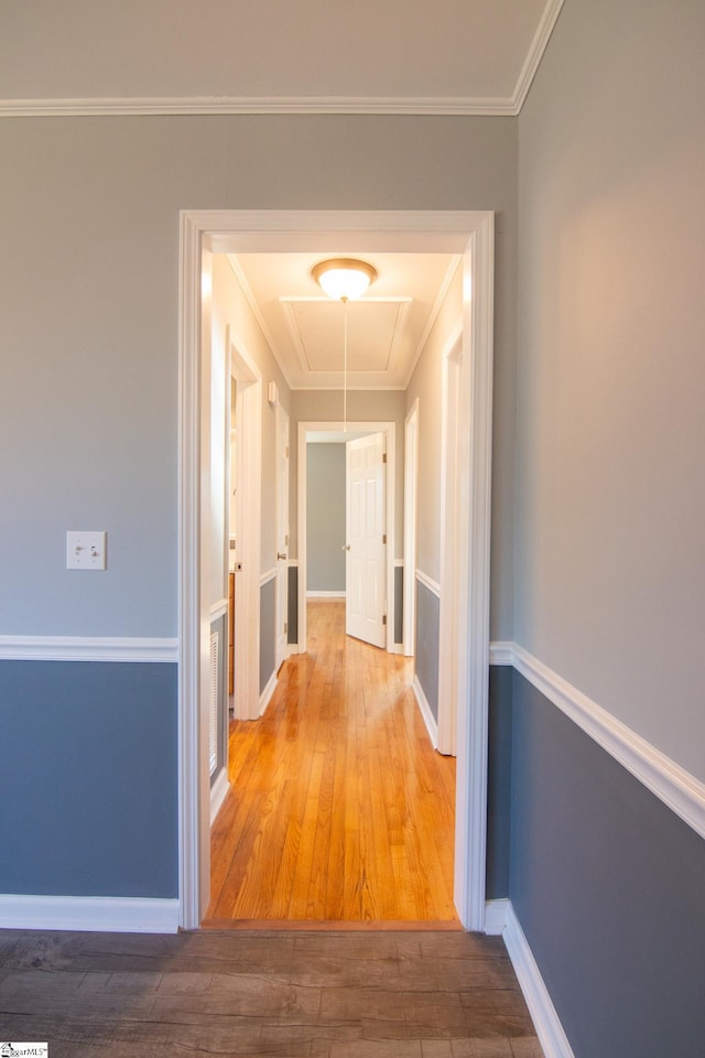 hallway with ornamental molding, wood finished floors, attic access, and baseboards