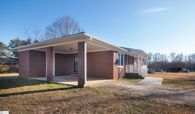 view of property exterior with an attached carport, concrete driveway, brick siding, and a yard