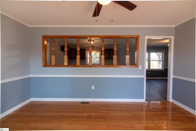 spare room featuring baseboards, wood finished floors, visible vents, and crown molding