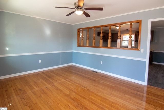 spare room featuring ornamental molding, wood finished floors, a ceiling fan, and baseboards