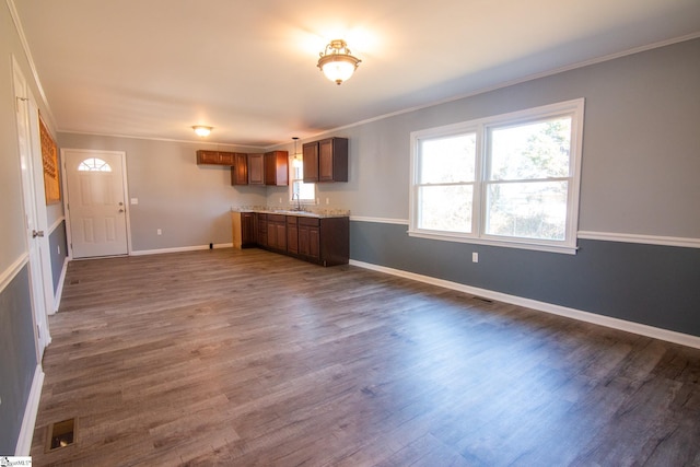 unfurnished living room with ornamental molding, dark wood-type flooring, a sink, and baseboards