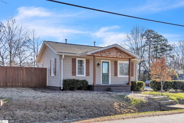 bungalow-style home featuring a porch, roof with shingles, and fence