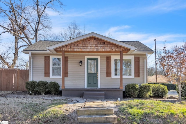 bungalow-style house featuring a porch, fence, and a shingled roof