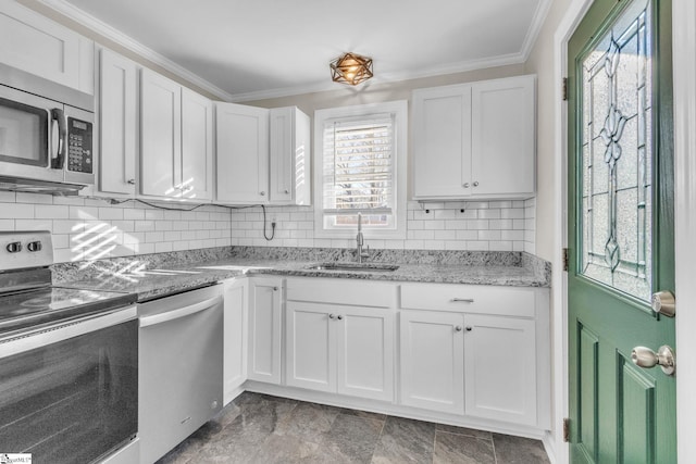 kitchen featuring appliances with stainless steel finishes, white cabinets, a sink, and ornamental molding