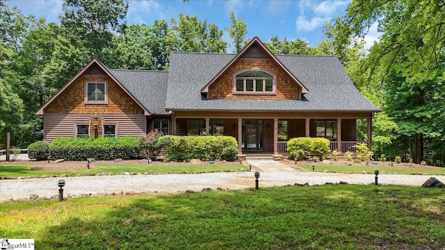 view of front of home with covered porch, a front lawn, and roof with shingles