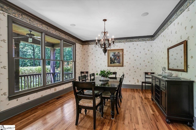 dining space with wallpapered walls, baseboards, crown molding, and wood finished floors