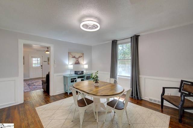 dining room with wood-type flooring, a wainscoted wall, and a textured ceiling