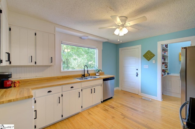 kitchen with light wood-style floors, appliances with stainless steel finishes, white cabinets, and a sink