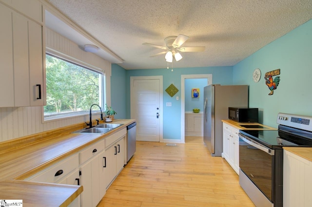 kitchen with appliances with stainless steel finishes, white cabinets, light countertops, and a sink