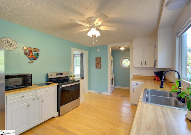 kitchen featuring stainless steel range with electric stovetop, black microwave, white cabinets, and a sink