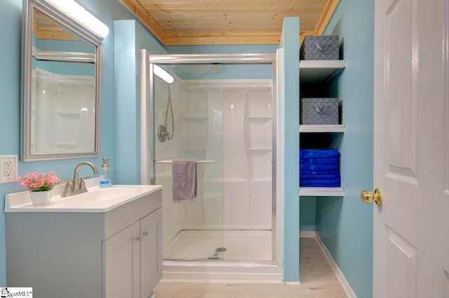 bathroom featuring a stall shower, baseboards, wooden ceiling, wood finished floors, and vanity