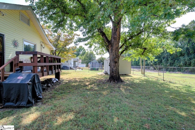 view of yard with a fenced backyard, a storage unit, and an outbuilding