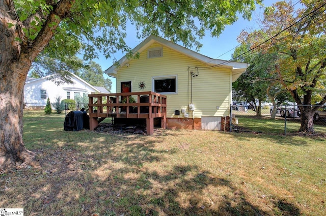 rear view of house featuring a yard, fence, and a wooden deck