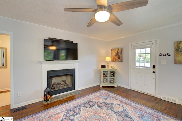 living room featuring a fireplace with flush hearth, visible vents, a textured ceiling, and wood finished floors