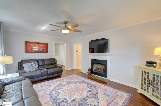 living room with a fireplace with flush hearth, crown molding, ceiling fan, and wood finished floors