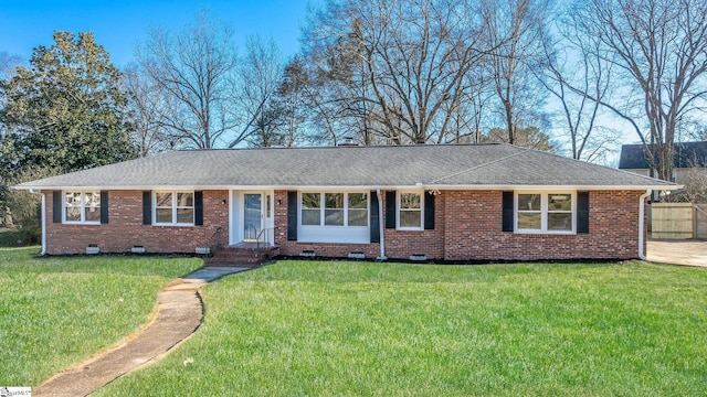 ranch-style home with crawl space, roof with shingles, a front yard, and brick siding