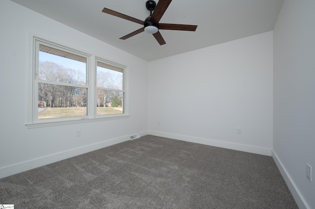 spare room with a ceiling fan, visible vents, dark carpet, and baseboards