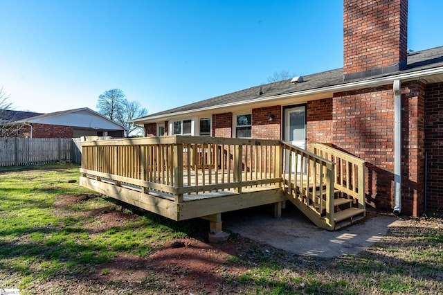 back of house featuring a wooden deck, a chimney, fence, a yard, and brick siding