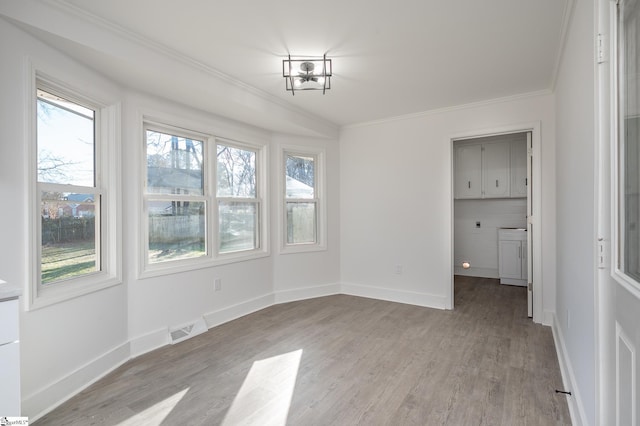 unfurnished dining area with plenty of natural light, baseboards, crown molding, and light wood finished floors