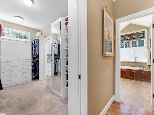 walk in closet featuring light carpet and vaulted ceiling